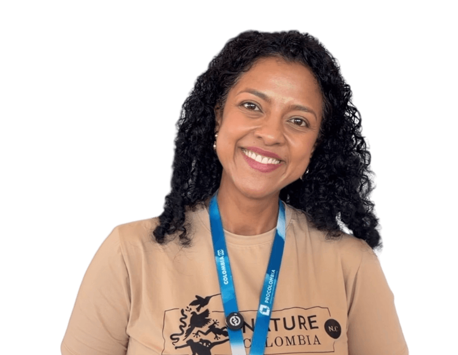 Mujer sonriente de cabello rizado y camiseta beige, con un cordón al cuello.
